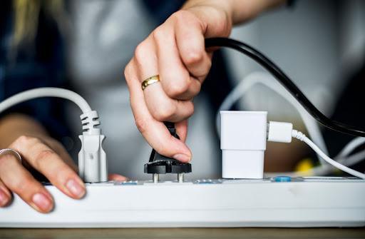 A person plugging a power cord into an extension cord.